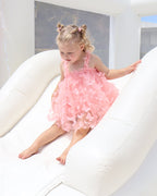 Two children playing on a colorful inflatable slide with a clear blue sky in the background.
